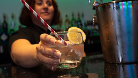 A member of bar staff at The Studio holding out a drink