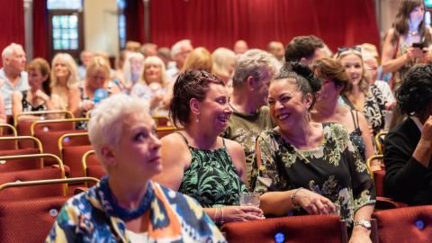 Two ladies chatting and laughing in the King's Hall auditorium.