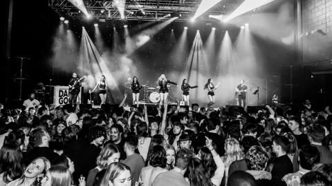 A black and white image of Taylor Swift tribute artist performing on stage in front of a crowd.