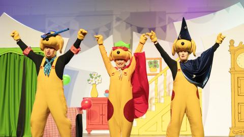 Three actors dressed as characters in Spots Birthday Party, wearing yellow dog costumes.