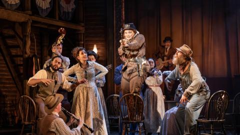 Production Image of Calamity Jane with Carrie Hope Fletcher in character as Calamity, with emsemble dressed in Western outfits.