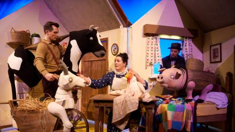 Cast of a children's theatre show performing on stage with farm yard animal puppets.