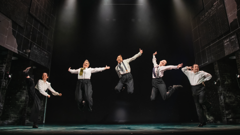 Five people in suits jumping in the air
