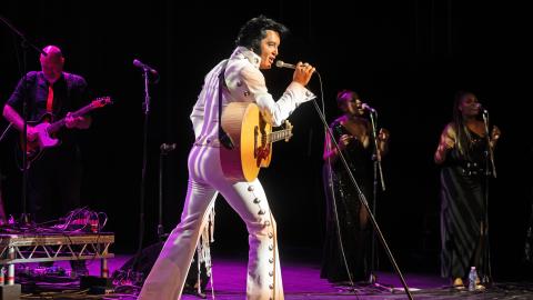 Ben Portsmouth as Elvis Presley, in a white and gold outfit and holding a microphone