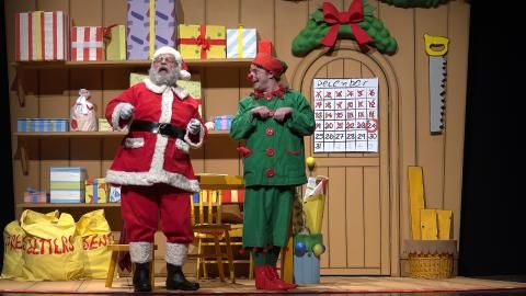 A man dressed as an elf and a man dressed as santa pretending to be reindeers