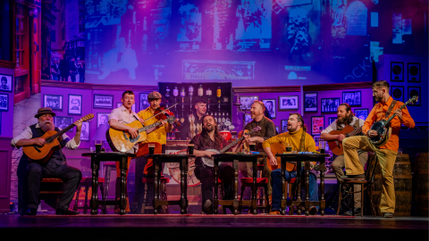 A group of musicians playing instruments on stage in a bar setting.