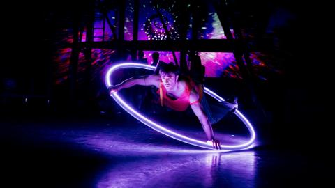 A performer in a hoop with bright purple lights.