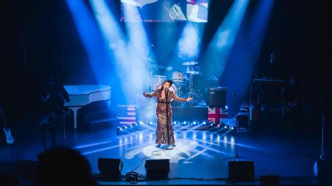A woman in a long dress sings into a microphone