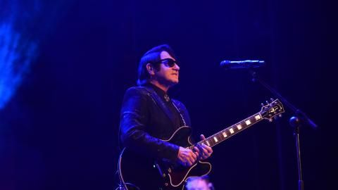 Barry Steele wearing sunglasses and playing the guitar, looking at the audience