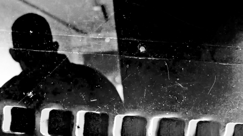 A black and white image in the style of the photographic negative with a silhouette of a man on the left.