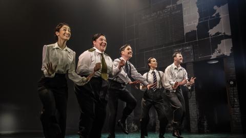 5 actors on stage in Operation Mincemeat wear white shirts with black trousers and ties.