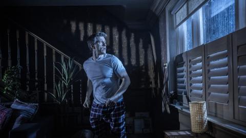 A man in a dark room looking out the window