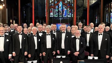 A group of men in tuxedos stand together in a church.