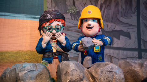 Actors in a Fireman Sam and Norman costume perform on stage.