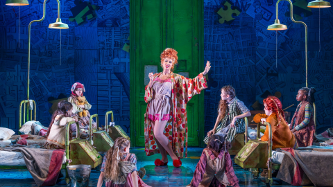 Claire Sweeney speaks to a group of young children on stage in Annie.