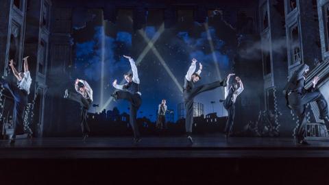 Male cast members of Matthew Bourne's Cinderella, leaping on stage wearing matching suits.