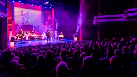 Barry Steele performing on stage surrounded by pink lighting.