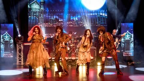 A group of singers perform on stage in Halloween costumes.
