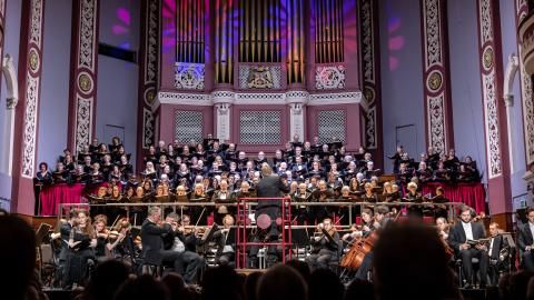 An orchestra and choir on stage at a large concert hall