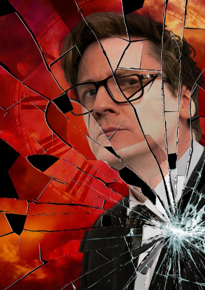 Comedian Ed Byrne stands behind a graphic of a red smashed clock