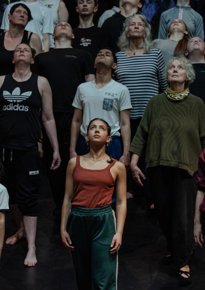 A group of people of all ages wearing casual clothes looking up.