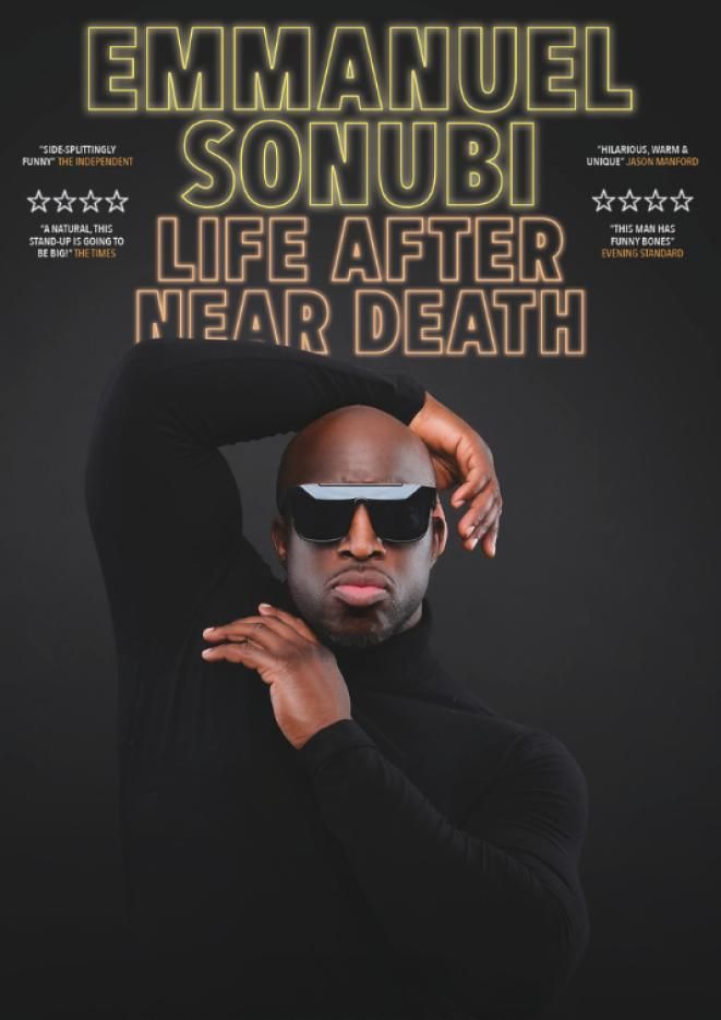 Comedian Emmanuel Sonubi poses against a black background wearing all black with sunglasses.