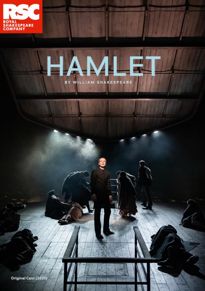 People dressed in all black stood on a tilting stage with smoke behind them. Above, text reads Hamlet.