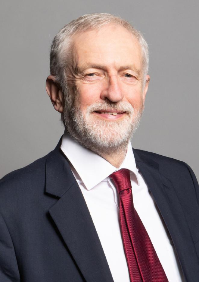 A close up image of politician Jeremy Corbyn wearing a suit with a red tie.