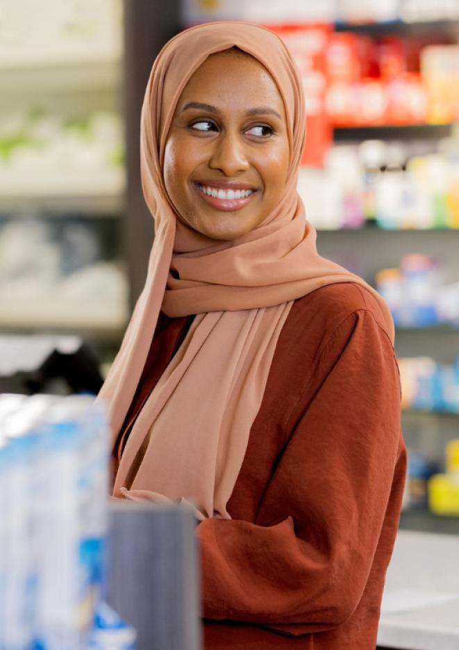 Comedian Ola Labib stands in a store wearing an orange outfit.