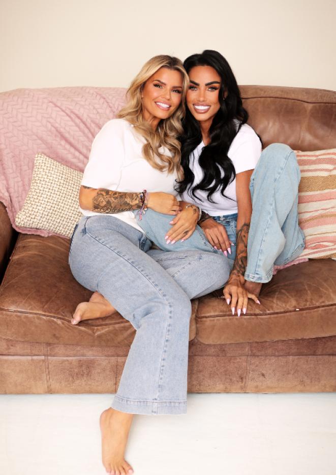 Two women sat on a couch in pale blue jeans and a white t-shirt