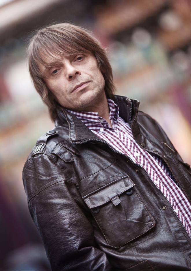 A close up image of musician Gary Mounfield wearing a brown leather jacket.