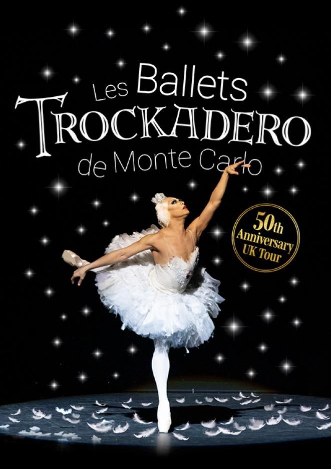 A male ballet dancer poses in a tutu in the centre of the image against a black background.