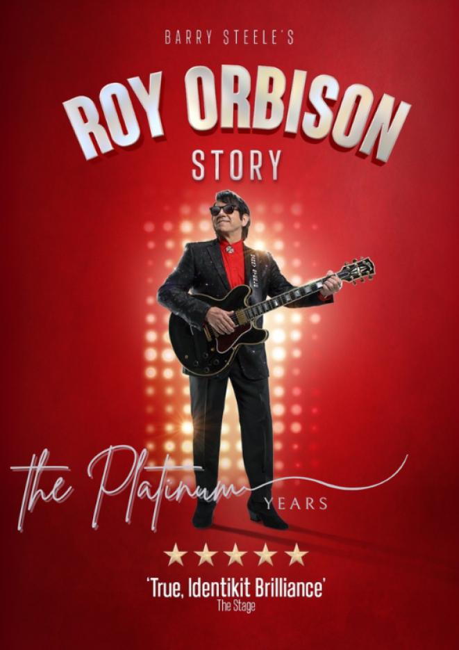 Barry Steele holding a guitar against a red backdrop