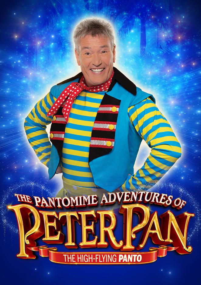 Billy Pearce in a blue and yellow striped t-shirt smiles at the camera with his hands on his hips, against a blue sparkly background