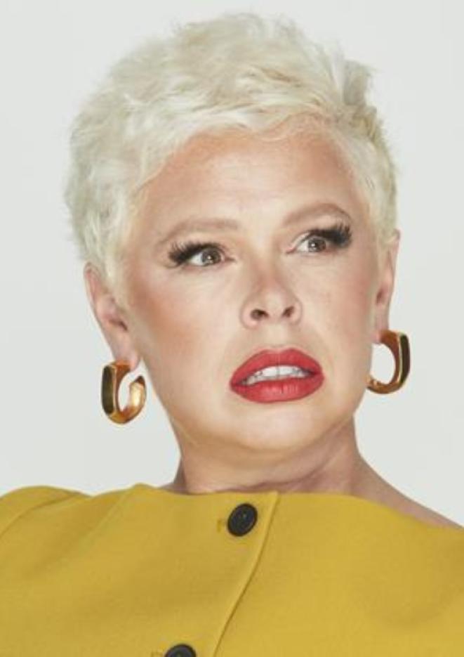 Comedian Laura Smyth looks off to the side, stood against a plain white background.