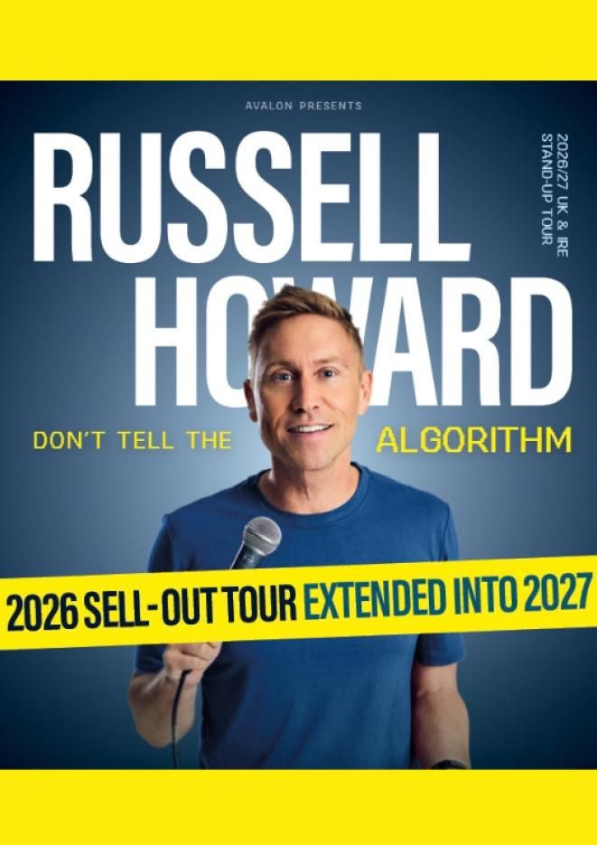 Comedian Russell Howard stands in the centre of the image holding a microphone.