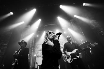 Black and white production image of The Bon Jovi Experience with three musicians singing and playing guitar.